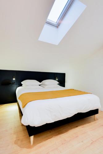 une chambre avec un grand lit avec une lucarne dans l'établissement Le Splendide de Poincaré, à Nancy