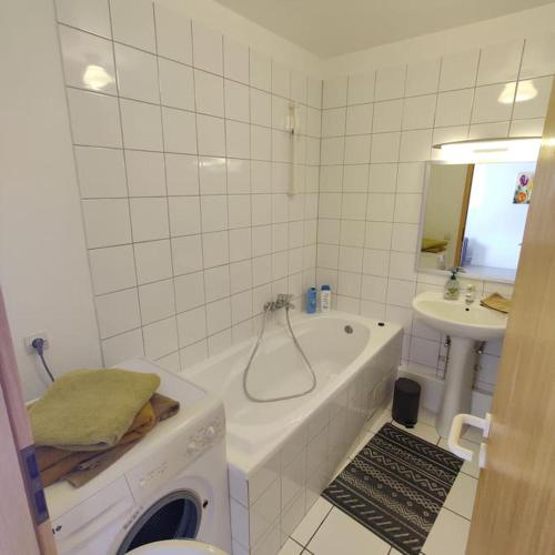 ein weißes Badezimmer mit einer Badewanne und einem Waschbecken in der Unterkunft Chez Arthur et Zoé. in Stiring-Wendel