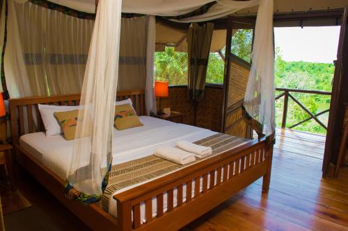 a bedroom with a bed with a mosquito net at Queen Elizabeth Bush Lodge by NATURE LODGES LTD in Bushenyi