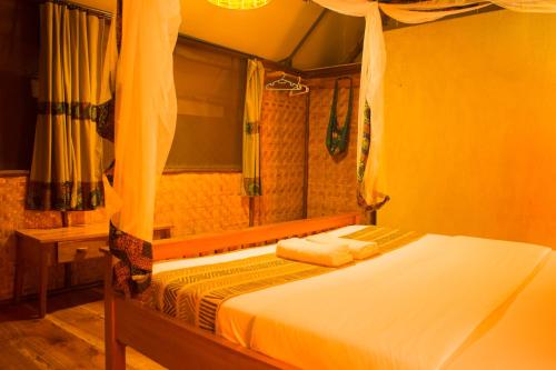 a bedroom with a bed and a mirror in a room at Queen Elizabeth Bush Lodge by NATURE LODGES LTD in Bushenyi