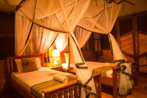 a bedroom with two beds with mosquito nets at Queen Elizabeth Bush Lodge by NATURE LODGES LTD in Bushenyi