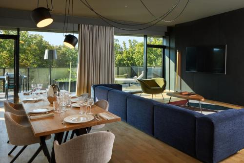 a dining room with a table and a blue couch at L'Esquisse Hotel & Spa Colmar - MGallery Collection in Colmar