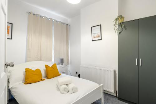 a bedroom with a white bed with yellow pillows at LiveStay - 5 Bedroom House in Stratford in London
