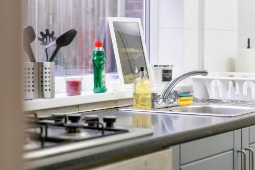 a kitchen counter with a stove and a sink at LiveStay - 5 Bedroom House in Stratford in London