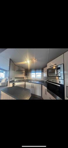 a kitchen with white cabinets and a stove top oven at Modern caravan Robin Hood Rhyl in Rhyl