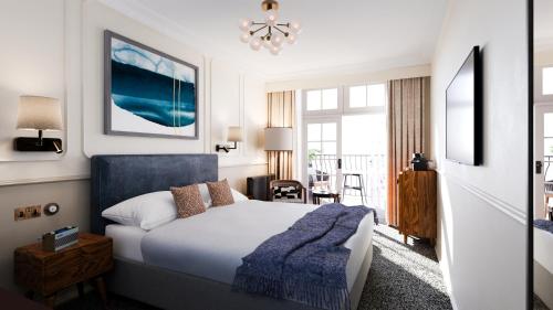 ein Schlafzimmer mit einem Bett mit einer blauen Decke in der Unterkunft White Horses by Everly Hotels Collection in Rottingdean