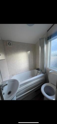 La salle de bains est pourvue d'une baignoire, d'un lavabo et de toilettes. dans l'établissement Modern caravan Robin Hood Rhyl, à Rhyl