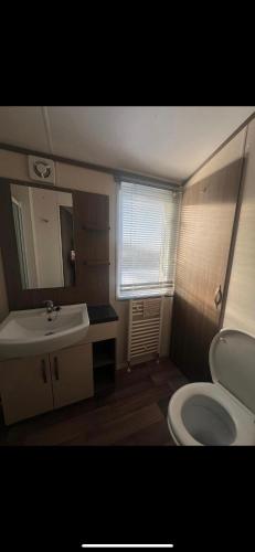 La salle de bains est pourvue d'un lavabo, de toilettes et d'un miroir. dans l'établissement Modern caravan Robin Hood Rhyl, à Rhyl