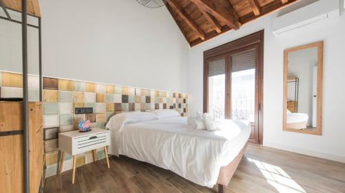 a bedroom with a white bed and a mirror at Apartamentos Granadal in Toledo