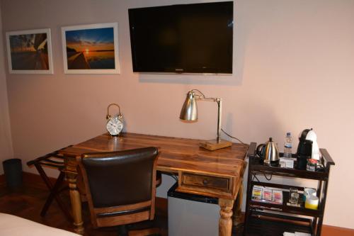 a wooden desk with a lamp and a television on a wall at GuestHouse 1109 in Maputo