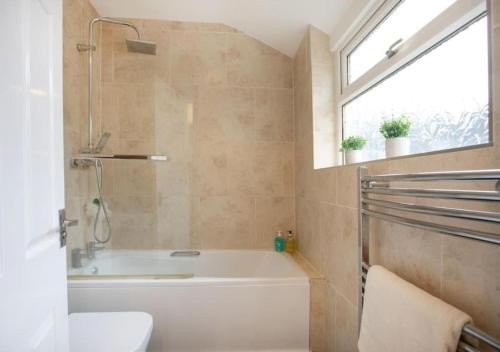 a bathroom with a tub and a sink and a window at 4 Bedroom Apartment with Essentials - free private parking, private check-in and check-out and free WiFi in Lincolnshire