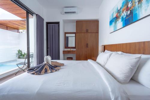 a bedroom with a white bed and a large window at The Lavana De Mello's Villa Seminyak -1 Bedroom Villa with Private Pool in Kerobokan