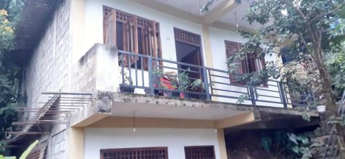 a white building with a balcony and a window at Daresh hime stay in Maskeliya