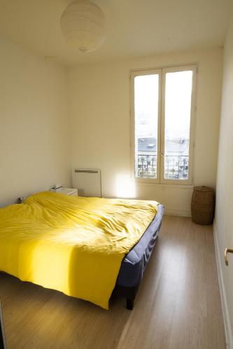 une chambre avec un grand lit avec un couvre-lit jaune dans l'établissement Paris La Défense Appartement, à Courbevoie
