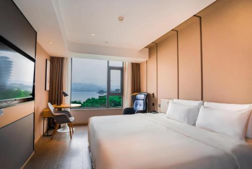 um quarto de hotel com uma cama grande e uma janela grande em Atour Hotel Hangzhou Qiandao Lake Central Dock em Chun'an