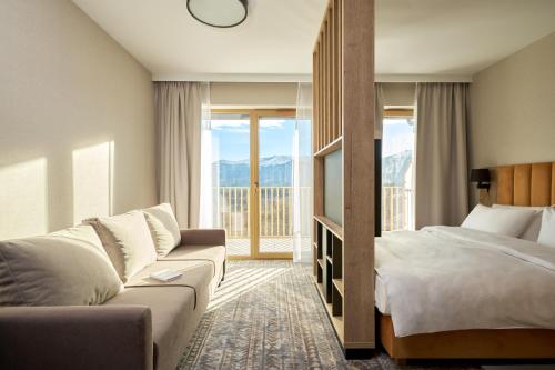 シュクラルスカ・ポレンバにあるZłoty Horyzont Resort Szklarska Porębaのベッドとソファ付きのホテルルーム