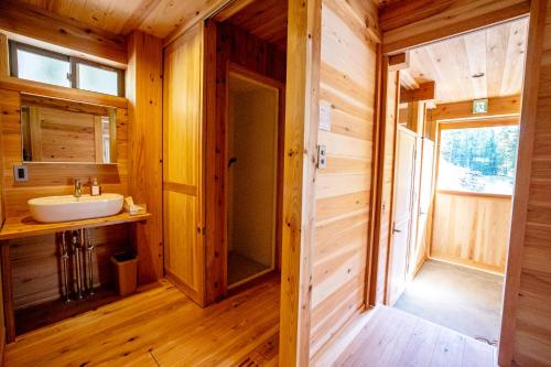 a bathroom with a sink in a wooden house at Ecommodation 百のやど in Aone