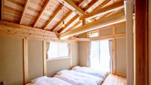 two beds in a room with a wooden ceiling at Ecommodation 百のやど in Aone