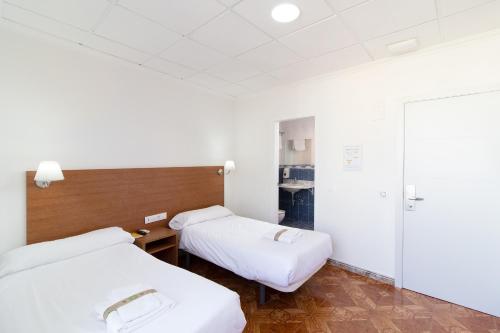 two beds in a hospital room with white sheets at Hotel Sagunto in Sagunto