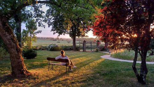 a woman sitting on a bench in a park at Le Manivert in Vitry-Laché