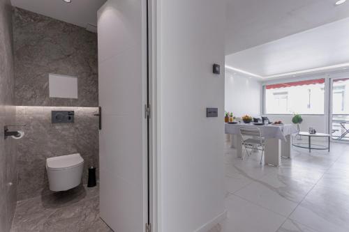 a white bathroom with a toilet and a dining room at L'unique Maubourg - Next Hotel Martinez - Terrasse in Cannes