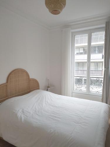 une chambre avec un lit blanc et une fenêtre dans l'établissement Stylish Parisian Flat near Eiffel Tower, à Paris