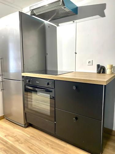 une cuisine avec une cuisinière et un réfrigérateur dans l'établissement Charmant gîte au bord de la Sarthe - 6 personnes, à Fillé