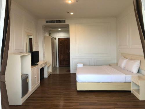 a bedroom with a white bed and a television at Golden Dragon Resort in Sing Buri