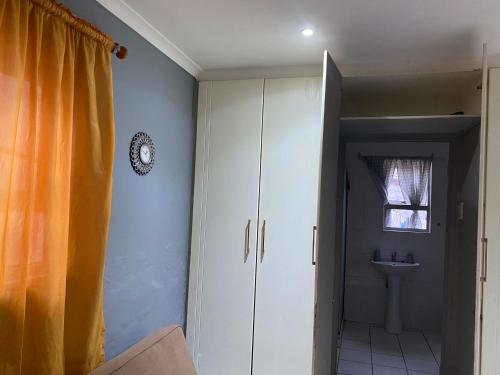 La salle de bains est pourvue d'une armoire blanche et d'un lavabo. dans l'établissement 4 Bedroom Family Home, à Port Elizabeth