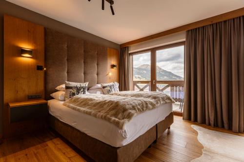 a bedroom with a large bed and a large window at Bergresort Zugspitze Ehrwald by ALPS RESORTS in Ehrwald