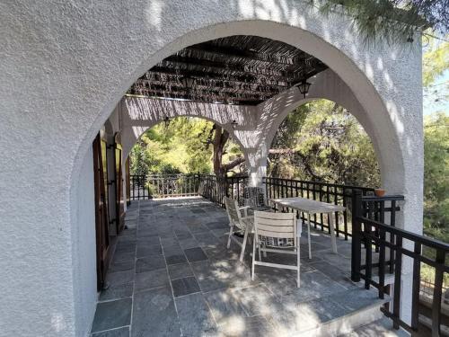 an archway with chairs and tables on a patio at Mike's Cycladic Villa in Poros