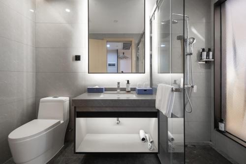 a bathroom with a sink and a toilet and a mirror at Jiayu Hotel - Guangzhou Baiyun International Airport T2 Terminal in Huadu