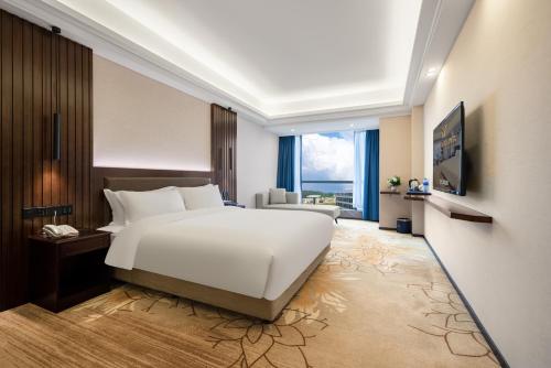 - une chambre avec un lit blanc et une grande fenêtre dans l'établissement Jiayu Hotel - Guangzhou Baiyun International Airport T2 Terminal, à Huadu