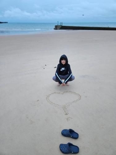 una mujer sentada en la playa con un corazón dibujado en la arena en Redcar Seaview Apartments, en Redcar