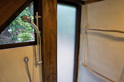 a shower in a room next to a window at Cabaña Chechen, wooden chalet in tropical garden in Isla Mujeres