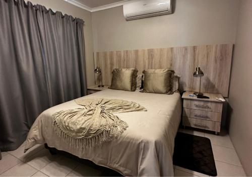 a bedroom with a large bed and a dresser with a lamp at 1020 Sehudi Guesthouse in Jwaneng