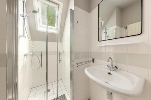 a white bathroom with a sink and a shower at Summio Vakantiepark It Wiid in Earnewâld