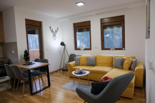a living room with a yellow couch and a table at Apartman Irvas Zlatibor in Zlatibor