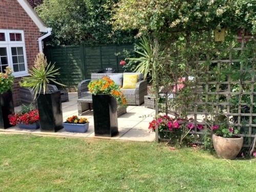 a garden with several pots of plants and flowers at Caedwalla House, Selsey in Selsey