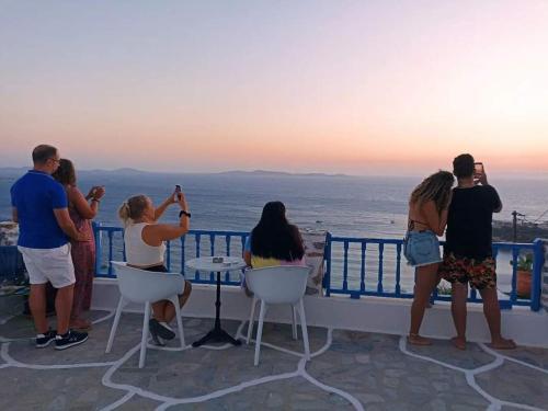 a group of people taking pictures of the ocean at Mykonos Rooms in Agios Stefanos