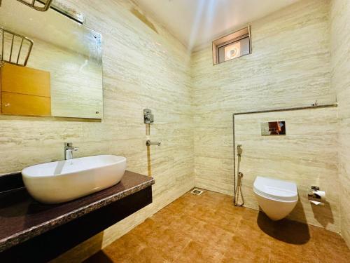 La salle de bains est pourvue d'un lavabo blanc et de toilettes. dans l'établissement Hotel Ultra International, à Siddharthanagar