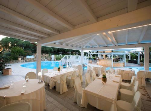 a restaurant with white tables and chairs and a pool at Hotel Sa Pedra in Murta Maria