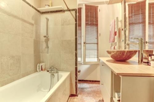 une salle de bain avec une baignoire et un lavabo dans l'établissement La Pompadour- Versailles, à Versailles