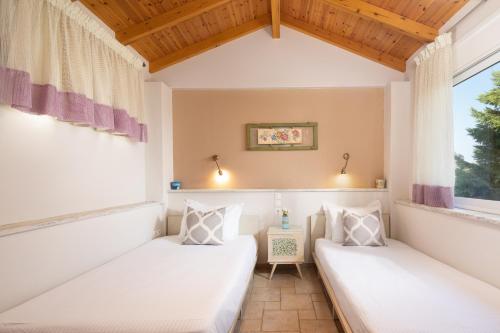 two beds in a room with a window at Cote Jardin in Barbati