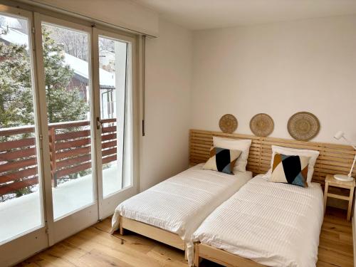 a bedroom with two beds and a large window at The Fit’ house in Crans-Montana