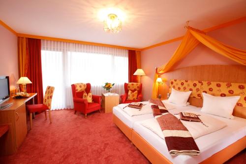 een hotelkamer met een groot bed en een televisie bij Ferienhotel Ödenhof in Baiersbronn
