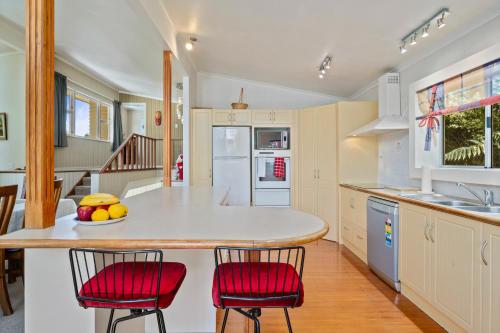 a kitchen with a counter and two red chairs at Pool House- Springfield in Rotorua