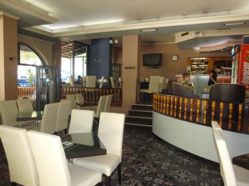 a restaurant with white chairs and a counter and a person at Joy Hotel in Sarandë