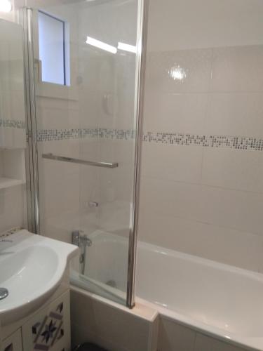 une salle de bain blanche avec une douche et un lavabo dans l'établissement Carro duplex les pieds dans l'eau et la tête dans les pins, à Martigues