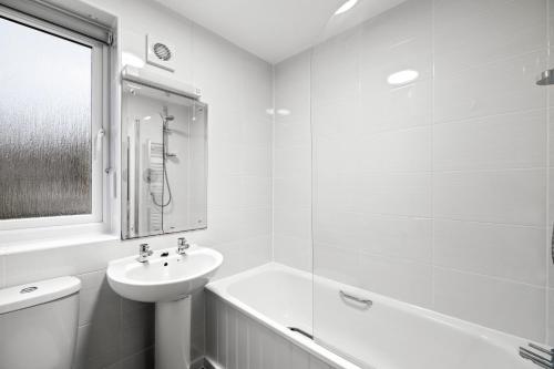 a white bathroom with a sink and a bath tub at Spacious Free Parking Contractors and Corporate in Exeter
